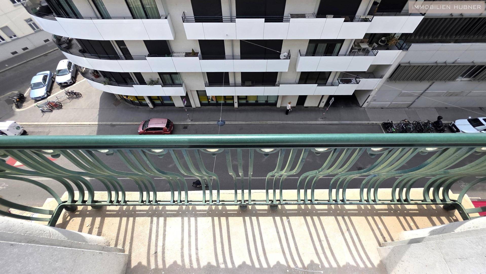 Blick vom Balkon auf die Straße und die umliegenden Gebäude, mit moderner Architektur im Hintergrund.