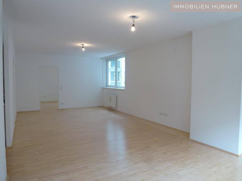 Geräumiges, helles Zimmer mit Parkettboden und mehreren Fenstern, ideal für Wohnzwecke.