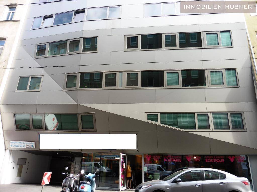 Moderne Gebäudefassade mit vielen Fenstern und Geschäftsflächen im Erdgeschoss, in urbaner Umgebung.