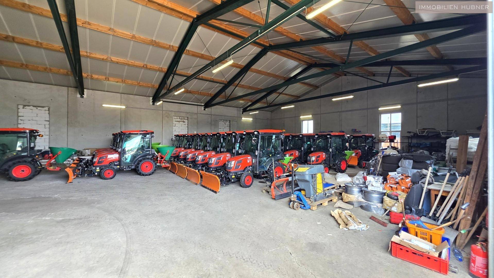 Geräumige Lagerhalle mit hoher Decke, vielen landwirtschaftlichen Maschinen und Lagergut.