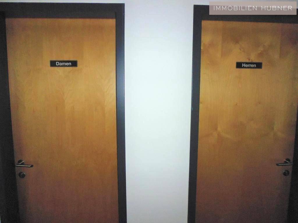 Zwei Holztüren, beschriftet mit 'Damen' und 'Herren', führen zu den getrennten Toilettenbereichen.