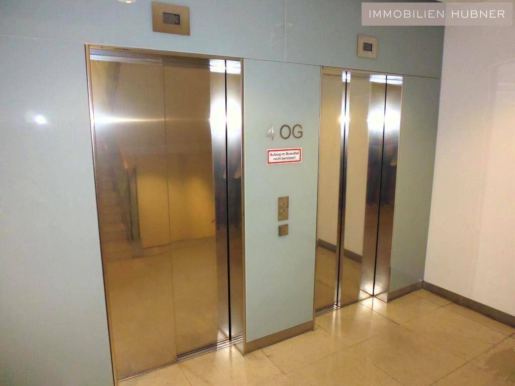 Zwei moderne Aufzüge mit glänzenden goldenen Türen in einem Flur, bereit zur Nutzung im Gebäude.