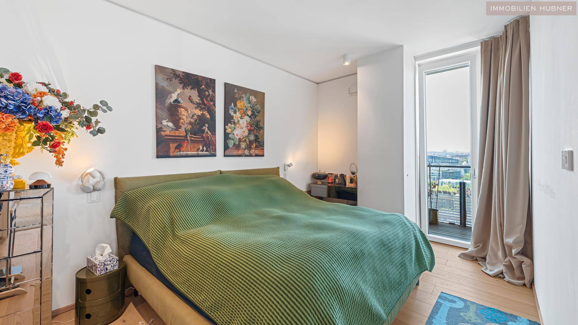 Gemütliches Schlafzimmer mit Doppelbett, Kunstwerken und Zugang zu einem kleinen Balkon.