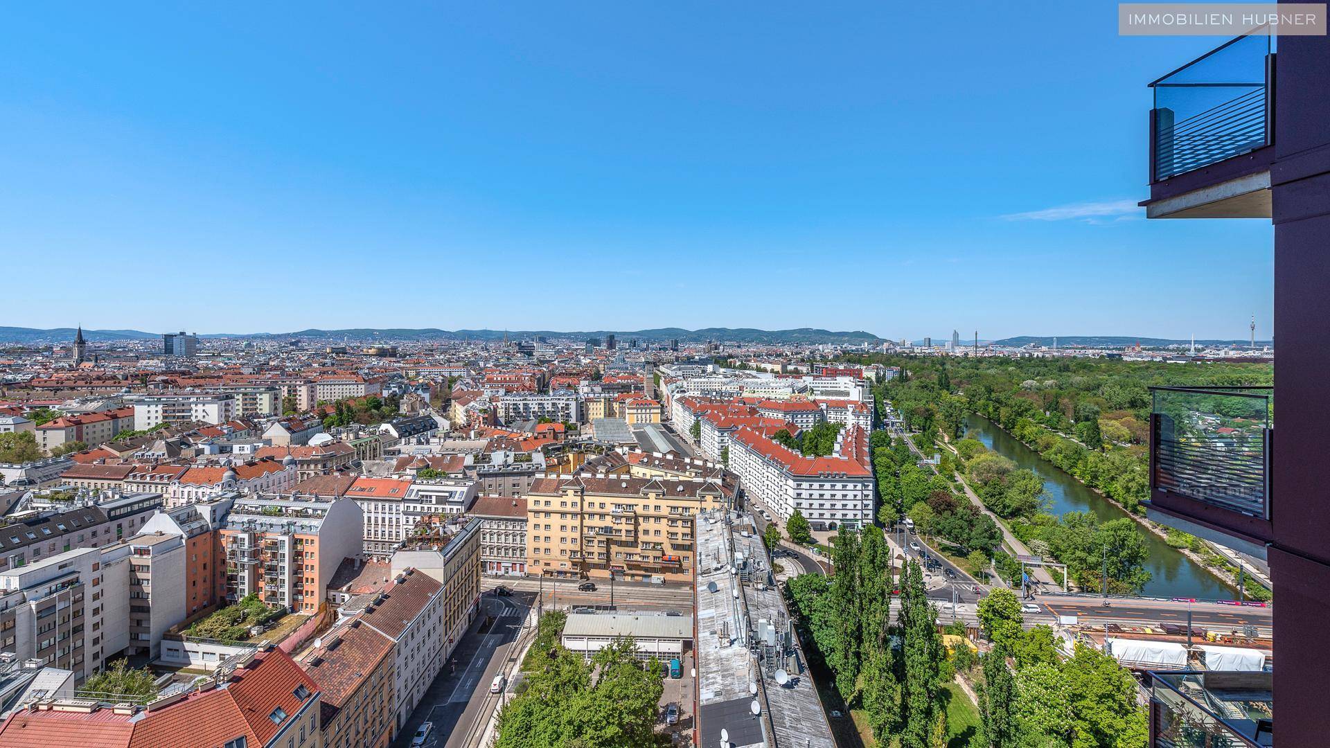 Panoramablick über die Stadt mit dicht bebauten Gebieten, einem Fluss und grünen Ufern.
