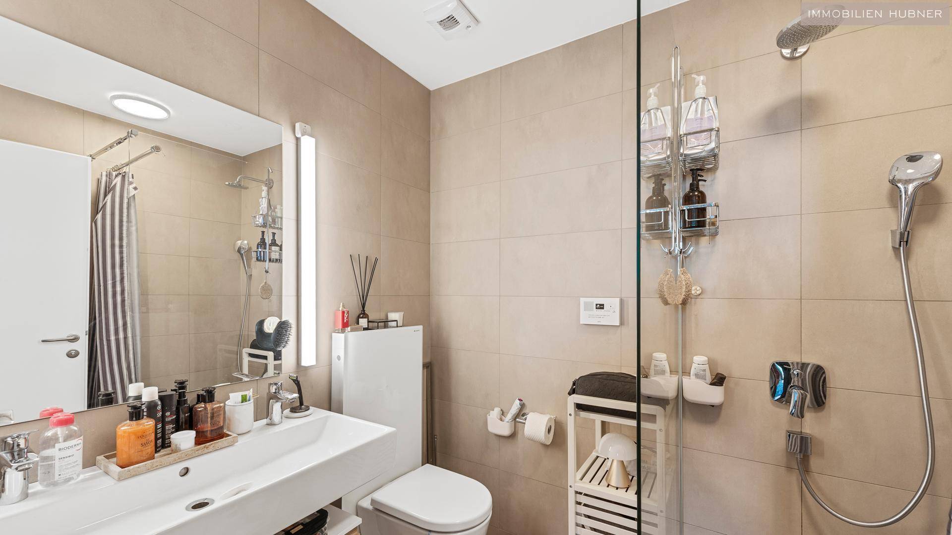 Helles Badezimmer mit Einzelwaschbecken, Toilette und Duschbereich, ausgestattet mit modernen Armaturen.