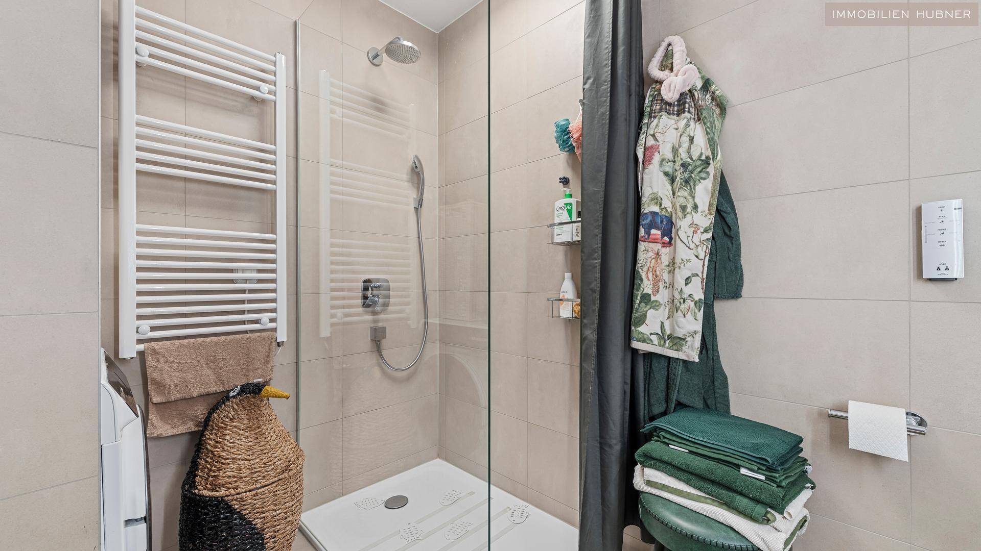 Modernes Badezimmer mit begehbarer Dusche, beigen Fliesen und einem beheizten Handtuchhalter.