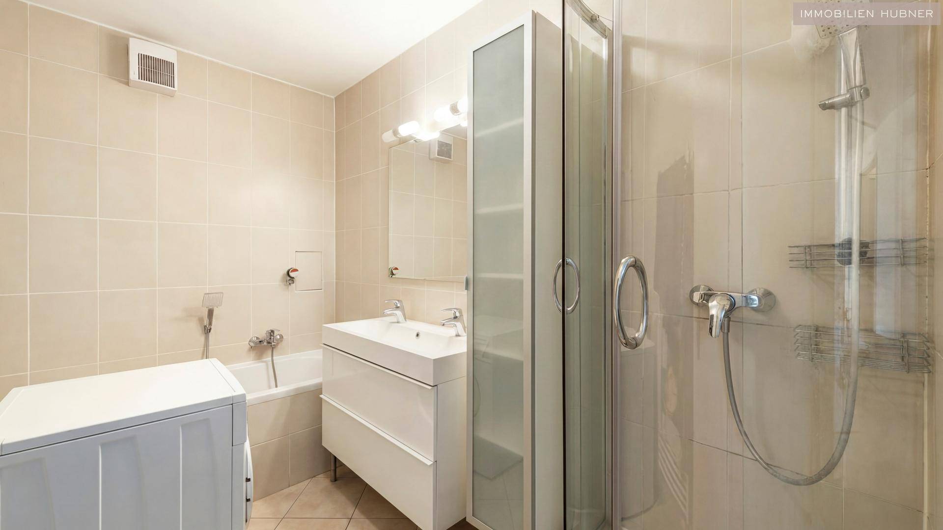 Modernes Badezimmer mit beigefarbenen Fliesen, Dusche, Badewanne und Waschbecken.