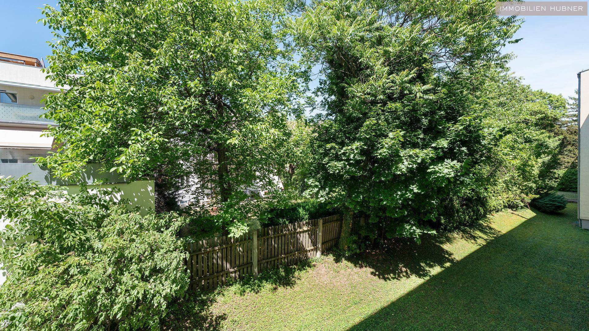 Gepflegter Gartenbereich mit üppigem Grün und einem Holzzaun, der Privatsphäre bietet.