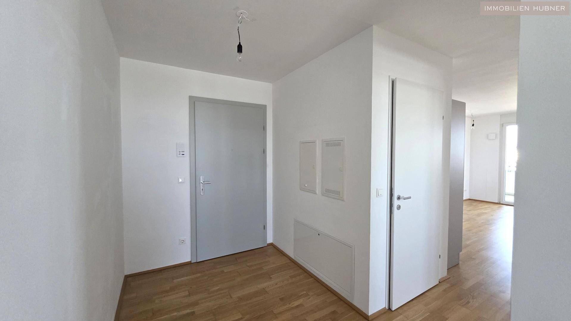 Heller Flur mit Holzboden und mehreren Türen, der zu den verschiedenen Räumen führt.