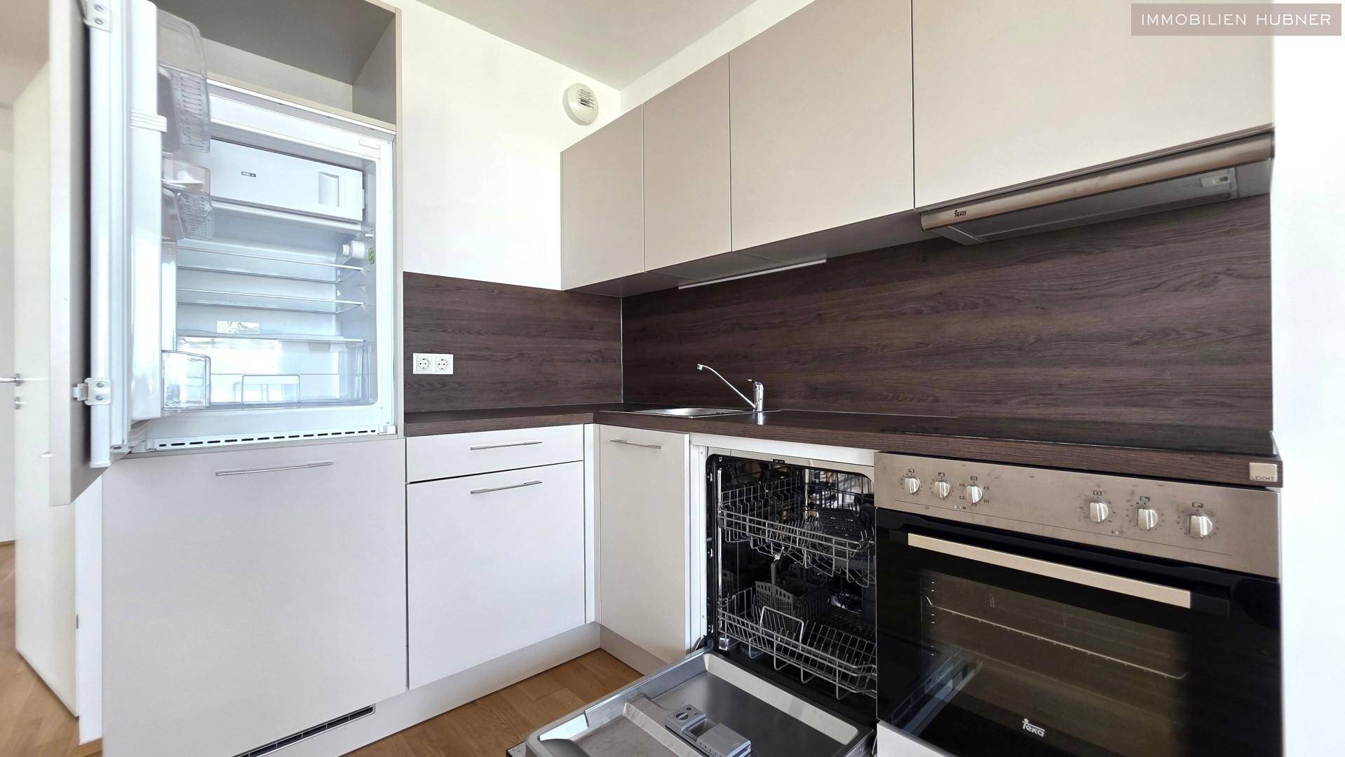 Voll ausgestattete Küche mit integriertem Kühlschrank und geöffnetem Geschirrspüler.