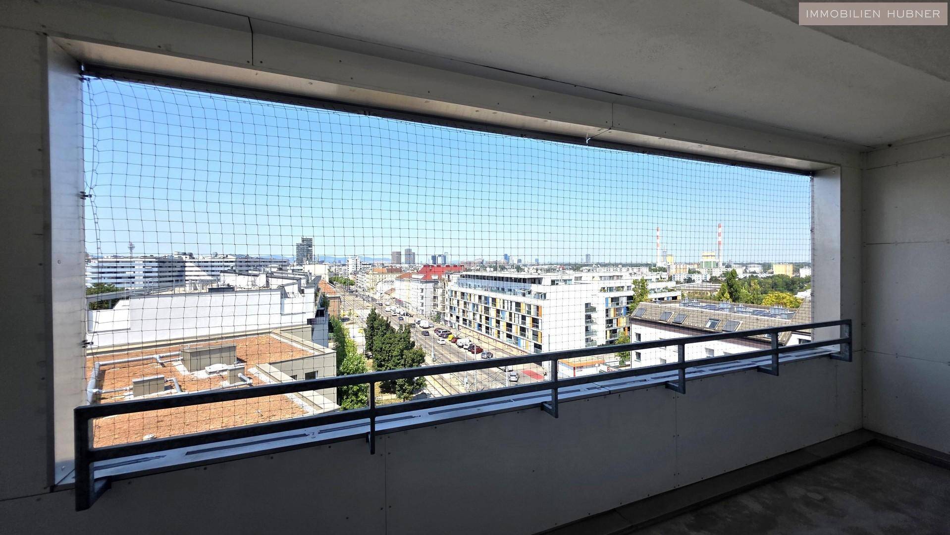 Balkon mit Schutznetz und weitem Blick über die Stadt und umliegende Gebäude.