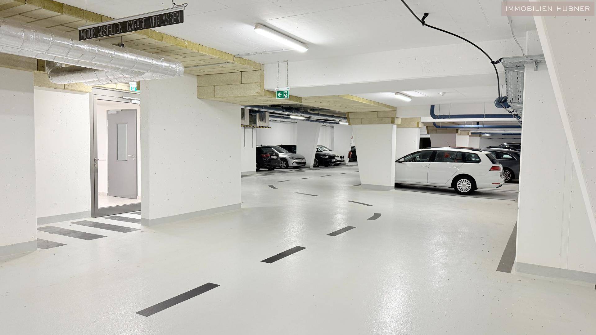 Saubere und helle Tiefgarage mit markierten Stellplätzen und guter Beleuchtung.