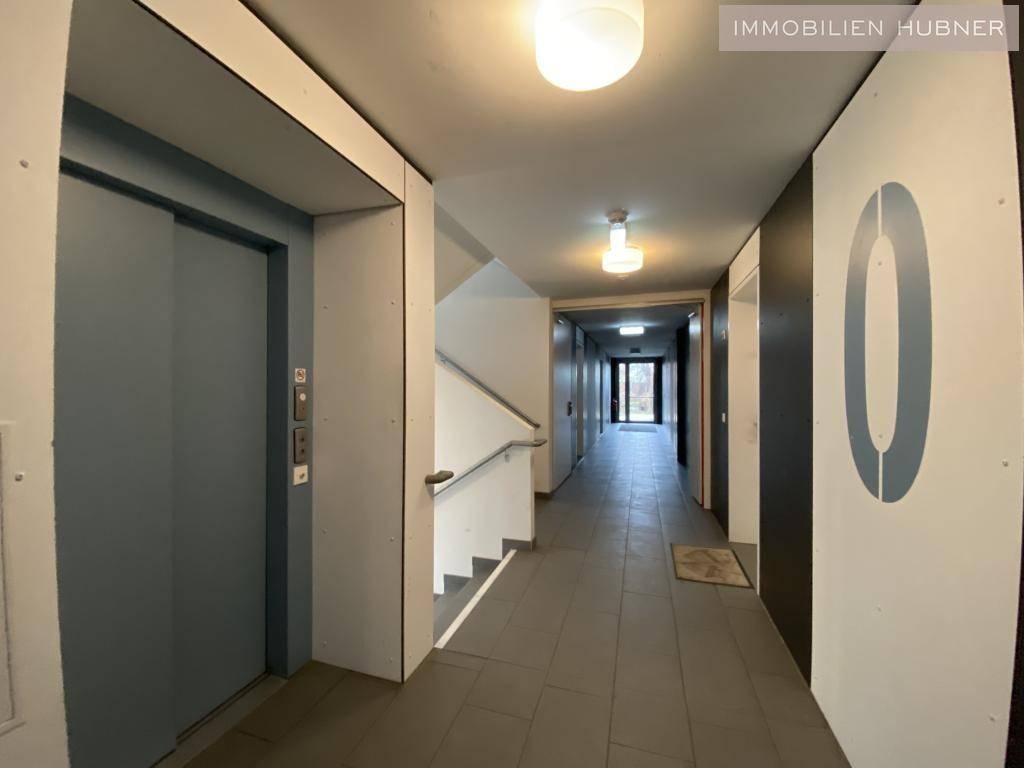 Heller Flur im Gebäude mit Aufzug und Treppenhaus, gut beleuchtet.