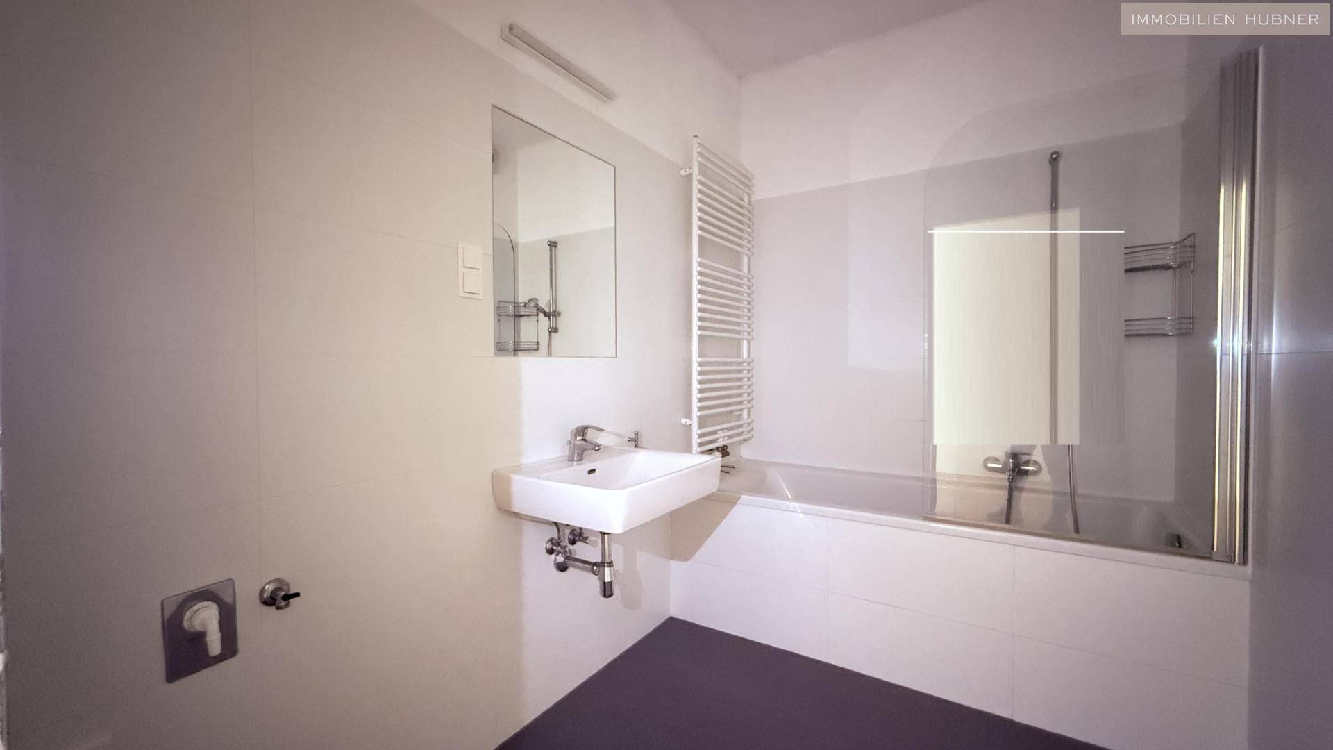 Modernes Badezimmer mit Badewanne, Einzelwaschbecken und beheiztem Handtuchhalter.