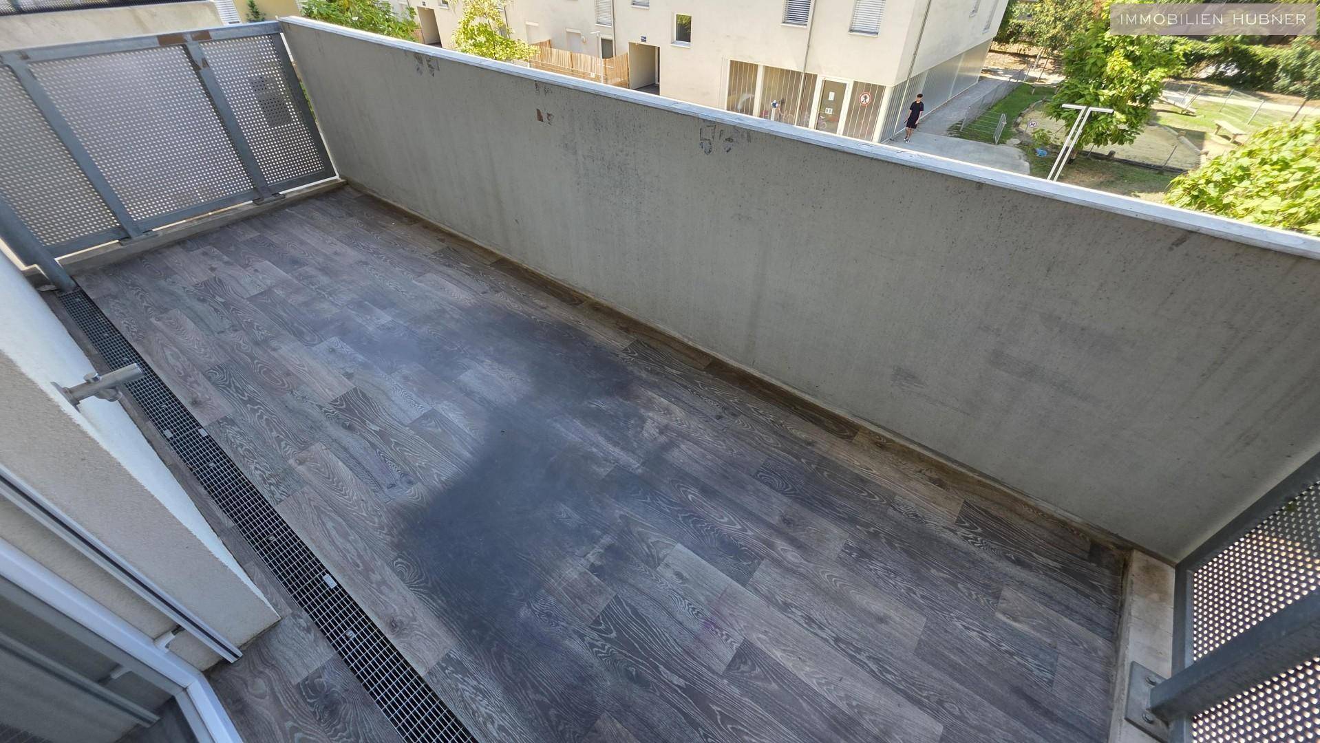 Geräumiger Balkon mit modernem Bodenbelag und Metallgeländer, bietet Platz für Entspannung im Freien.