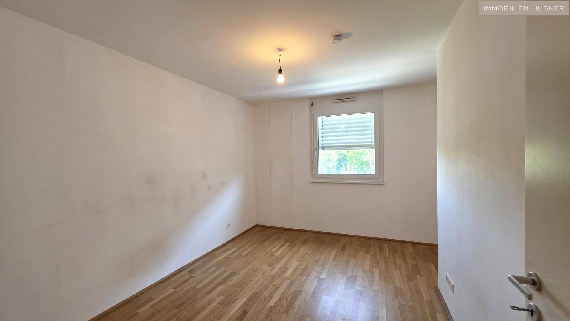 Weiteres helles Schlafzimmer mit Parkettboden und Fenster, ideal als Kinder- oder Gästezimmer.