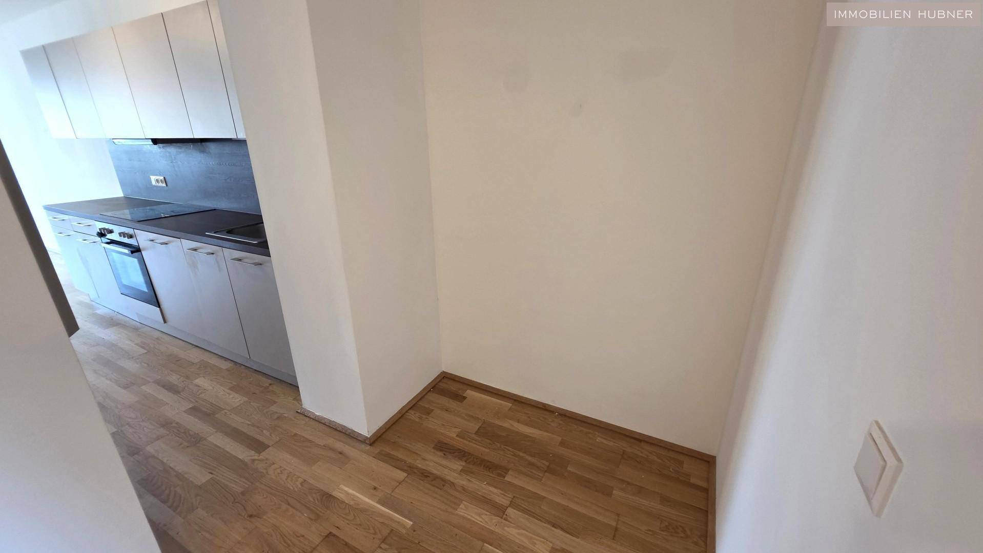 Detailansicht der Küchenzeile mit modernen Schränken und Parkettboden im offenen Wohnbereich.