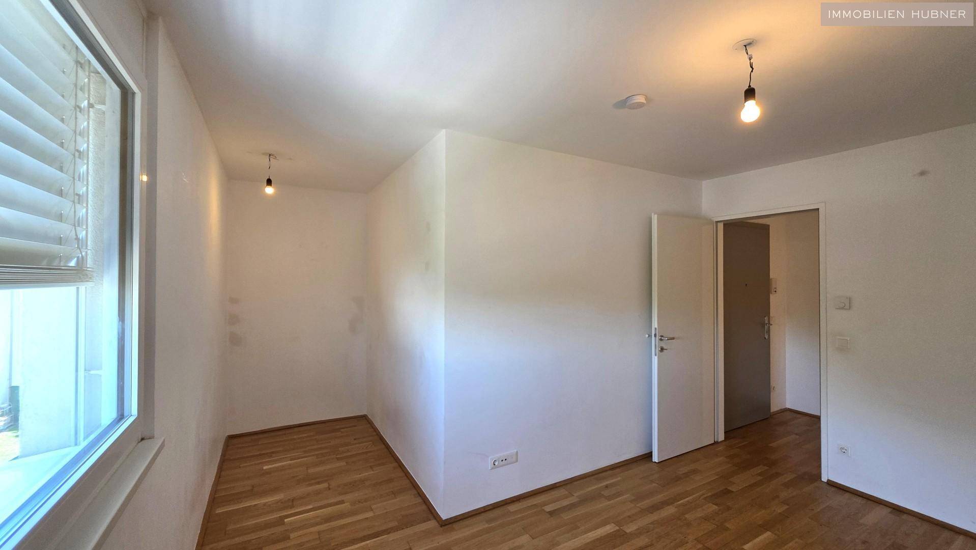 Geräumiges Zimmer mit Parkettboden und Fenster, vielseitig nutzbar als Schlaf- oder Arbeitszimmer.