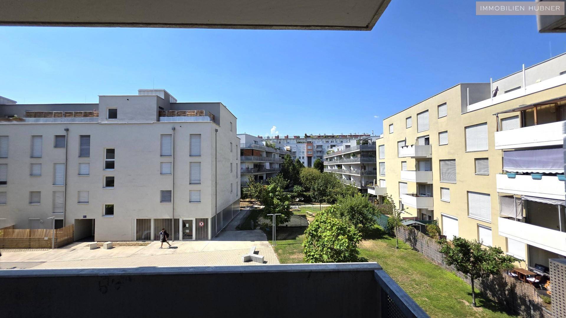 Blick vom Balkon auf die umliegenden Wohngebäude und eine grüne Innenhofanlage.