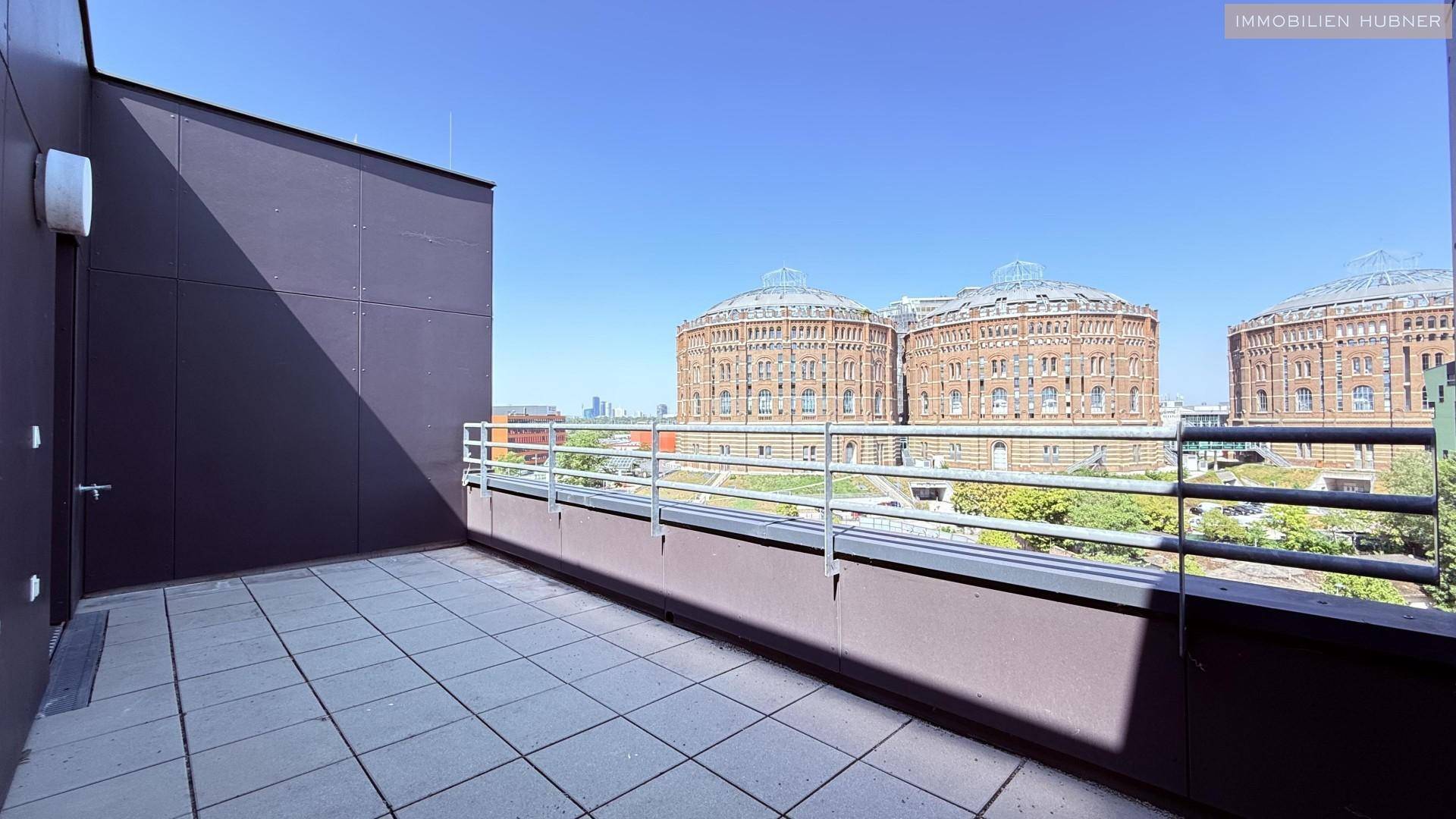 Geräumige Terrasse mit Fliesenboden und weitem Blick auf die historischen Gasometer.