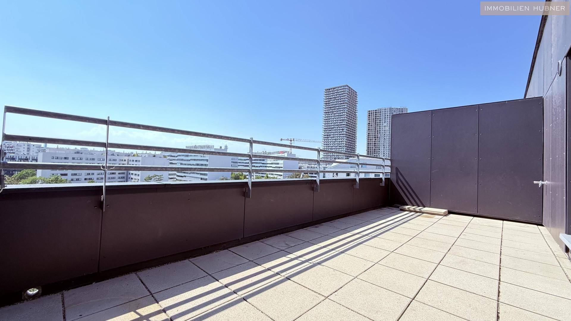 Weitläufige Terrasse mit Fliesenboden und urbanem Ausblick auf die umliegende Stadtlandschaft.