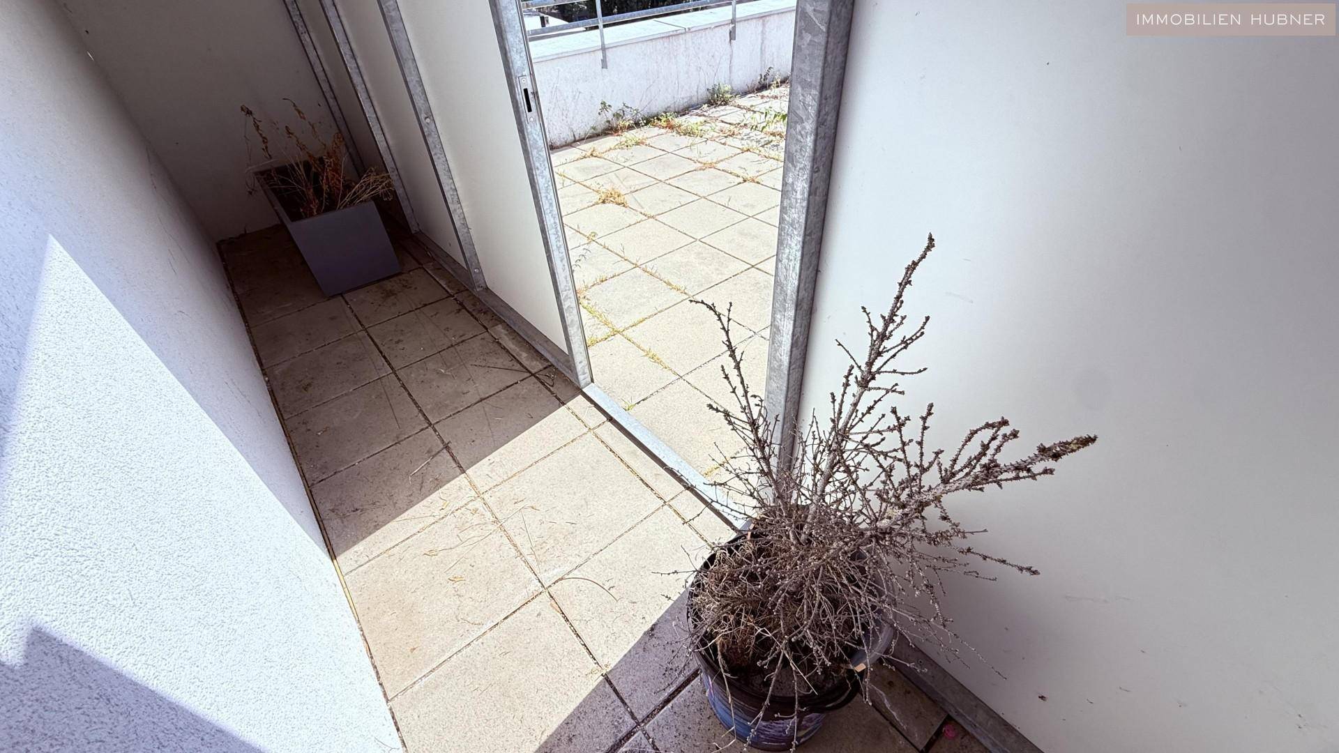 Kleiner Balkon mit Fliesenboden und Blick ins Grüne, ideal für Pflanzen.