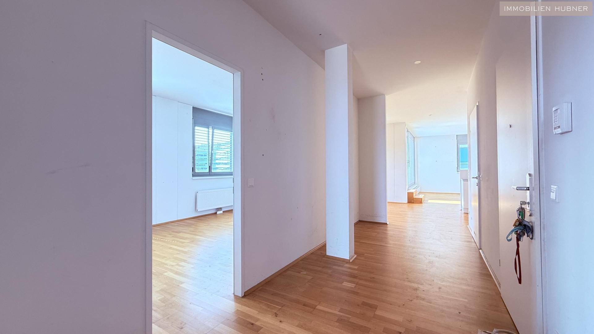 Heller Flur mit Parkettboden, der zu den verschiedenen Räumen der Wohnung führt.