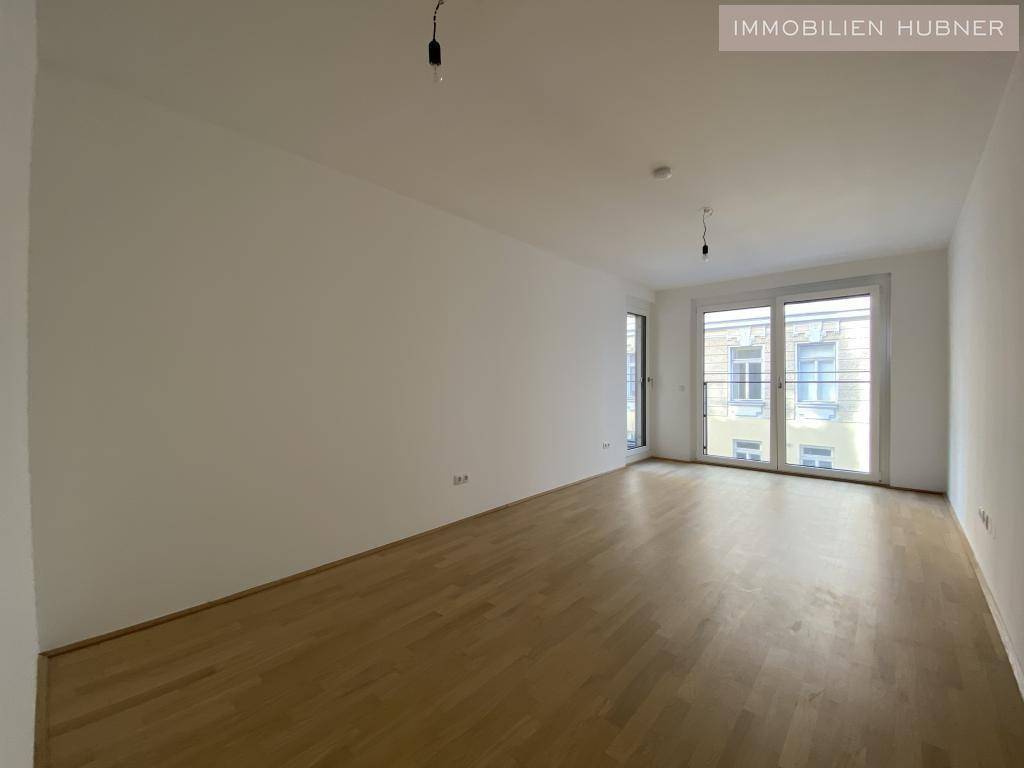 Geräumiges Zimmer mit Parkettboden und großen Fenstern, ideal als Schlafzimmer nutzbar.