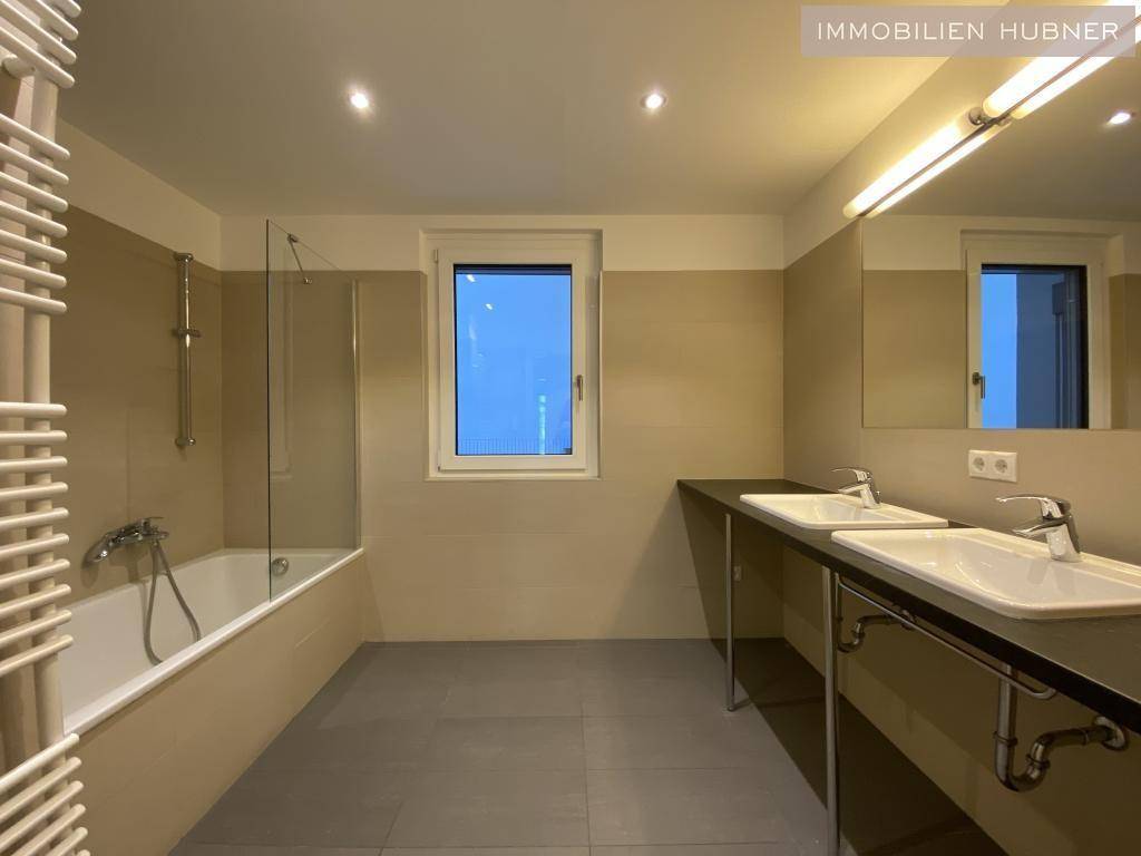Modernes Badezimmer mit Doppelwaschbecken, Badewanne und beheiztem Handtuchhalter.