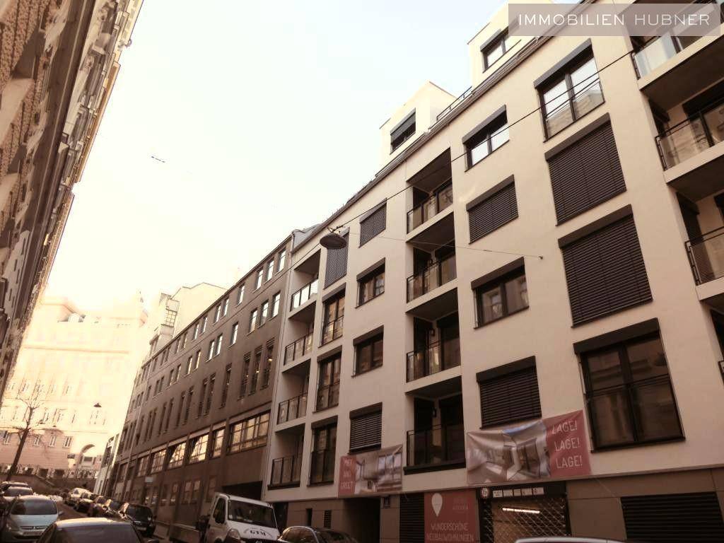 Moderne Wohngebäude-Fassade mit vielen Fenstern und Balkonen in urbaner Umgebung.
