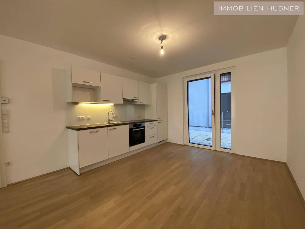 Moderne Küchenzeile in Weiß mit integrierten Geräten und Zugang zur Terrasse.