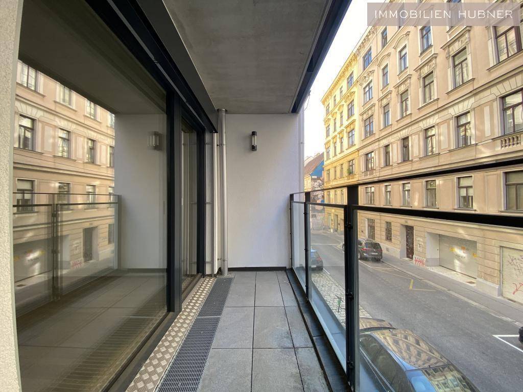 Schmaler Balkon mit Glasgeländer und Blick auf die belebte Stadtstraße.