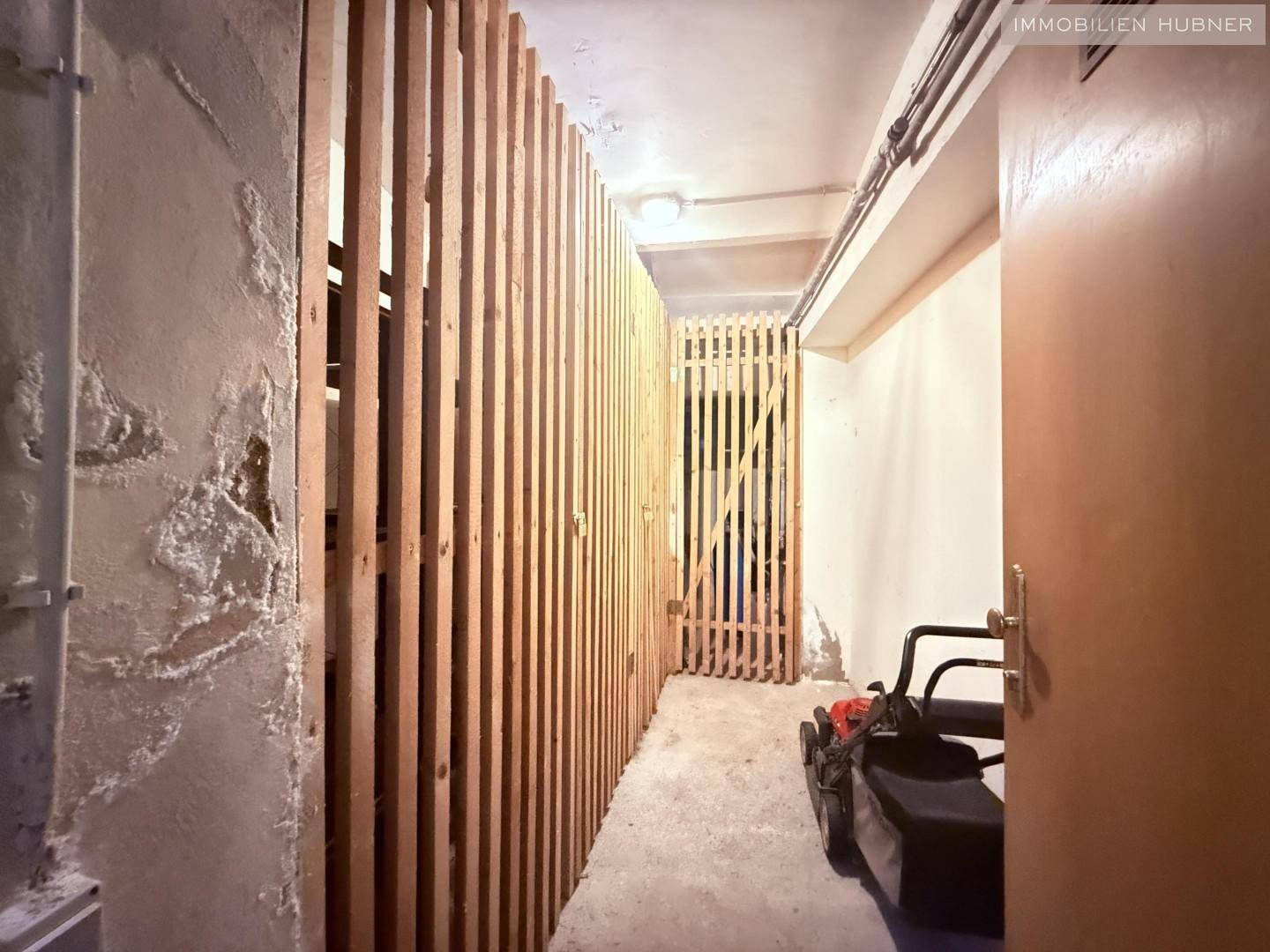 Kellerabteil mit Holzlattenwänden, ideal zur Lagerung von persönlichen Gegenständen.