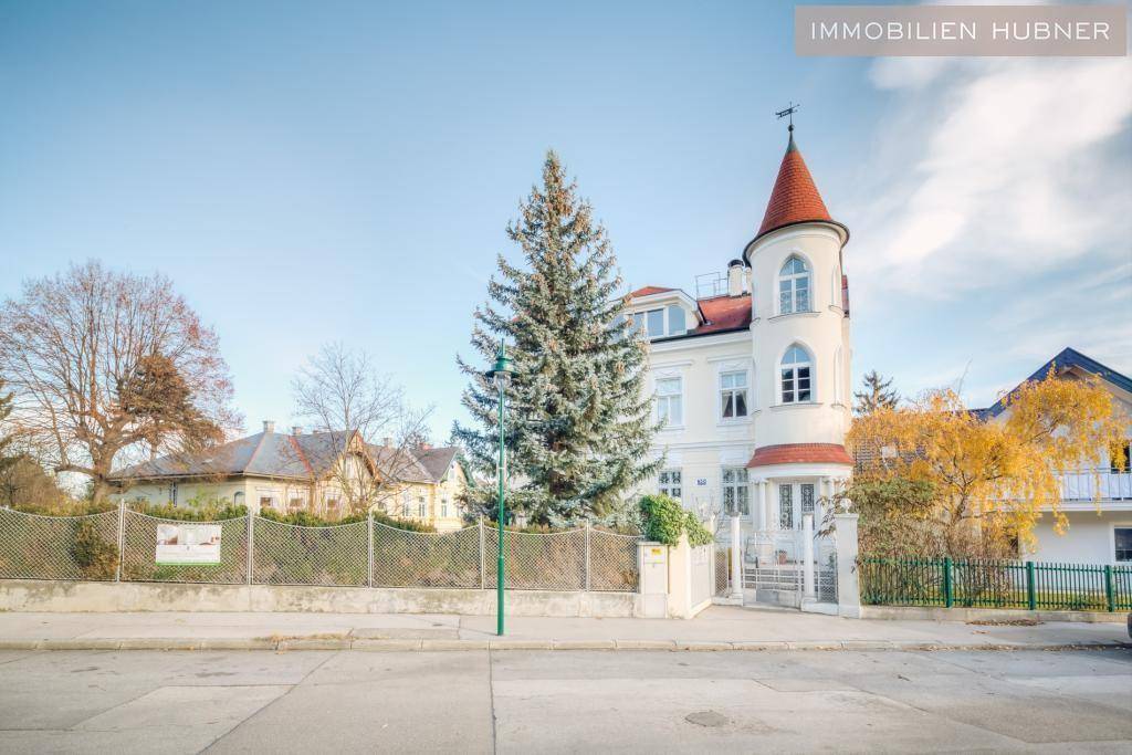 Elegantes Gebäude mit historischer Architektur und einem markanten Turm an der Straße.