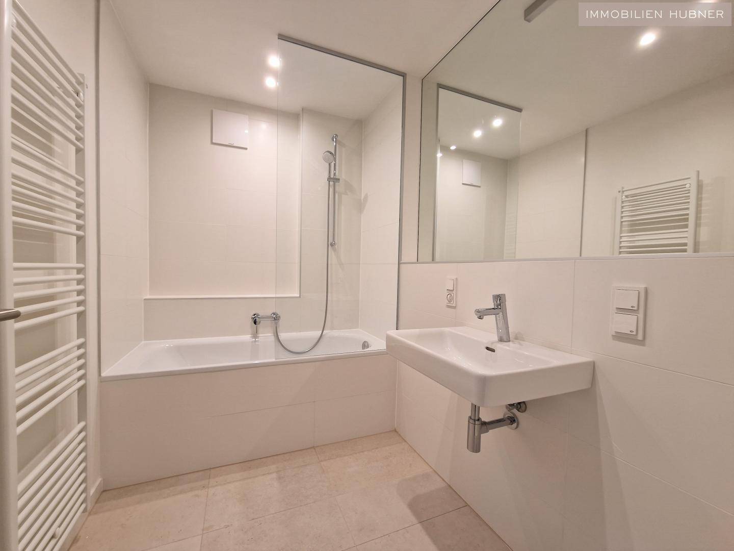 Modernes Badezimmer mit Badewanne, integrierter Dusche, Waschbecken und Handtuchheizkörper.