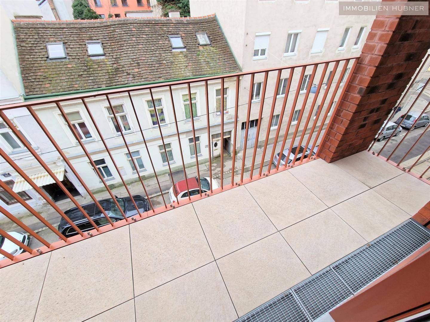 Geräumiger Balkon mit Fliesenboden und Blick auf die umliegende Stadtbebauung.