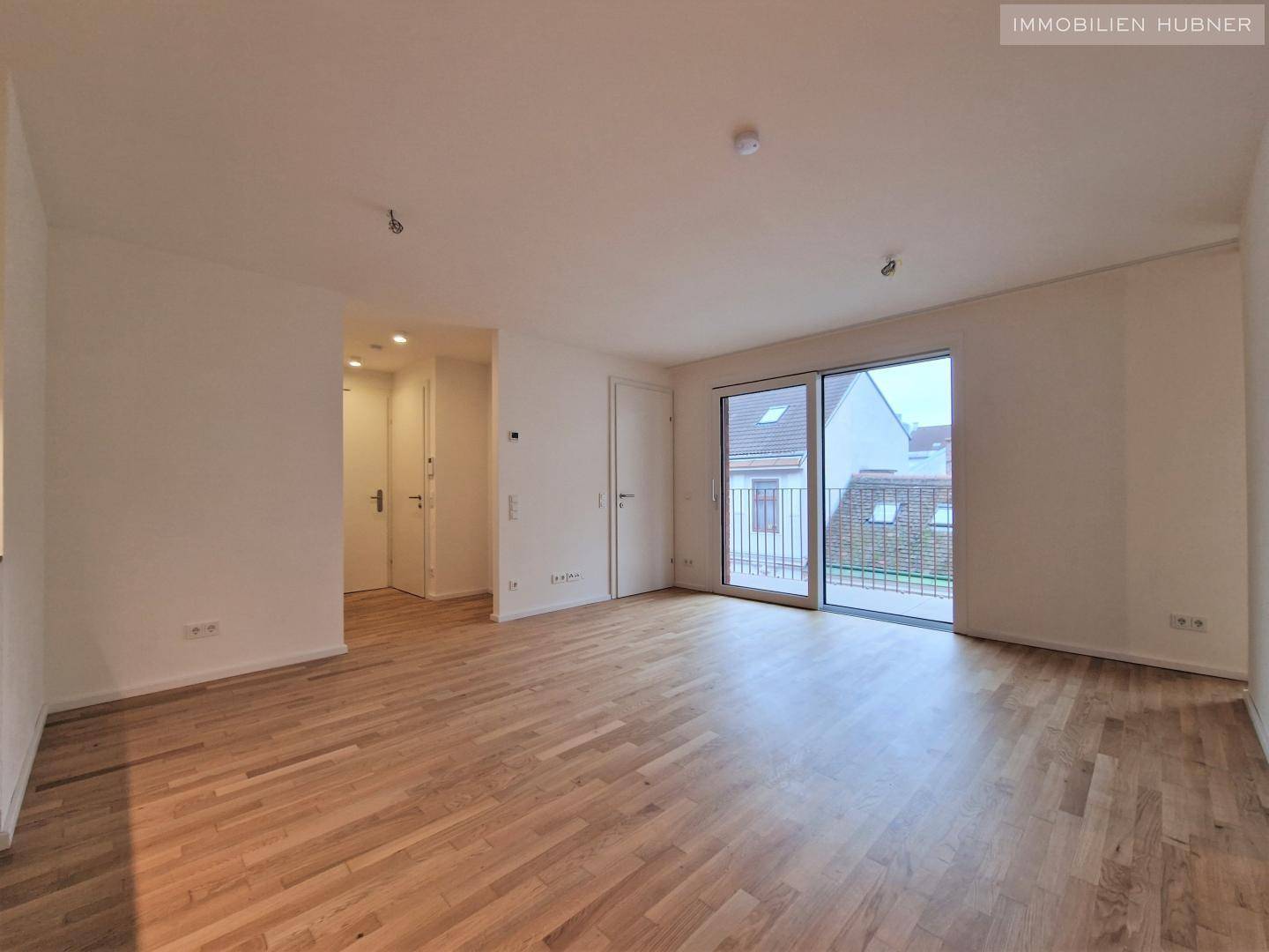 Heller Wohnraum mit Holzboden und Zugang zu einem Balkon, ideal für individuelle Gestaltung.