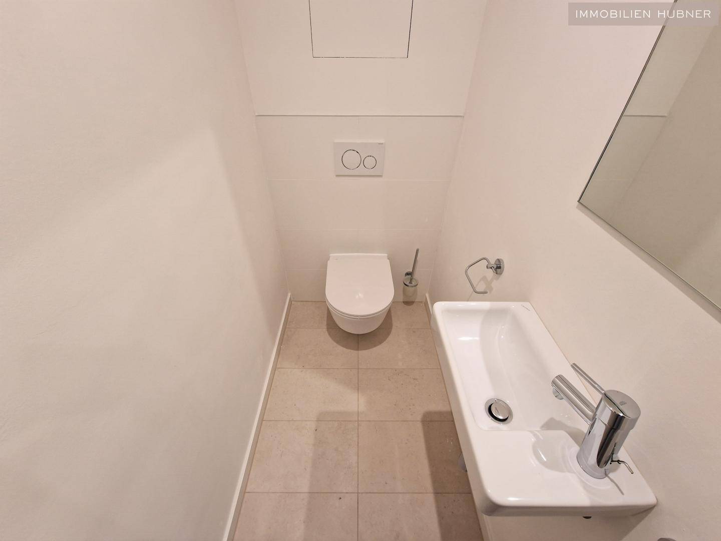 Separates Gäste-WC mit wandhängendem WC und kleinem Handwaschbecken.