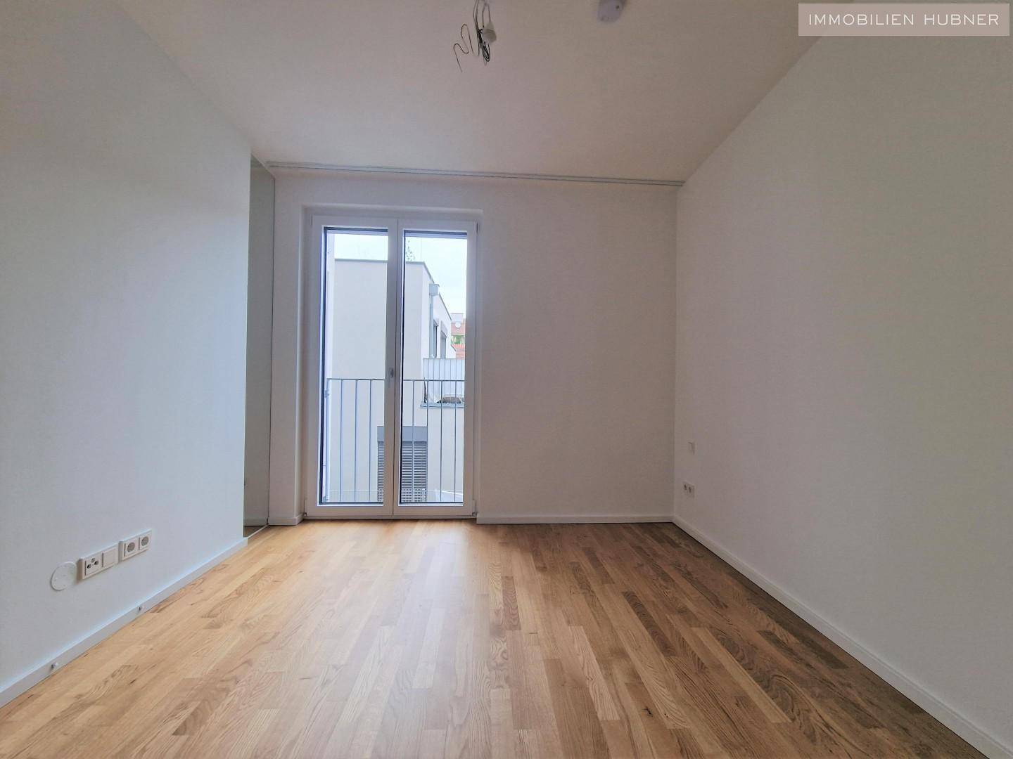 Helles Zimmer mit Parkettboden und Zugang zu einem französischen Balkon, ideal als Schlaf- oder Arbeitszimmer.