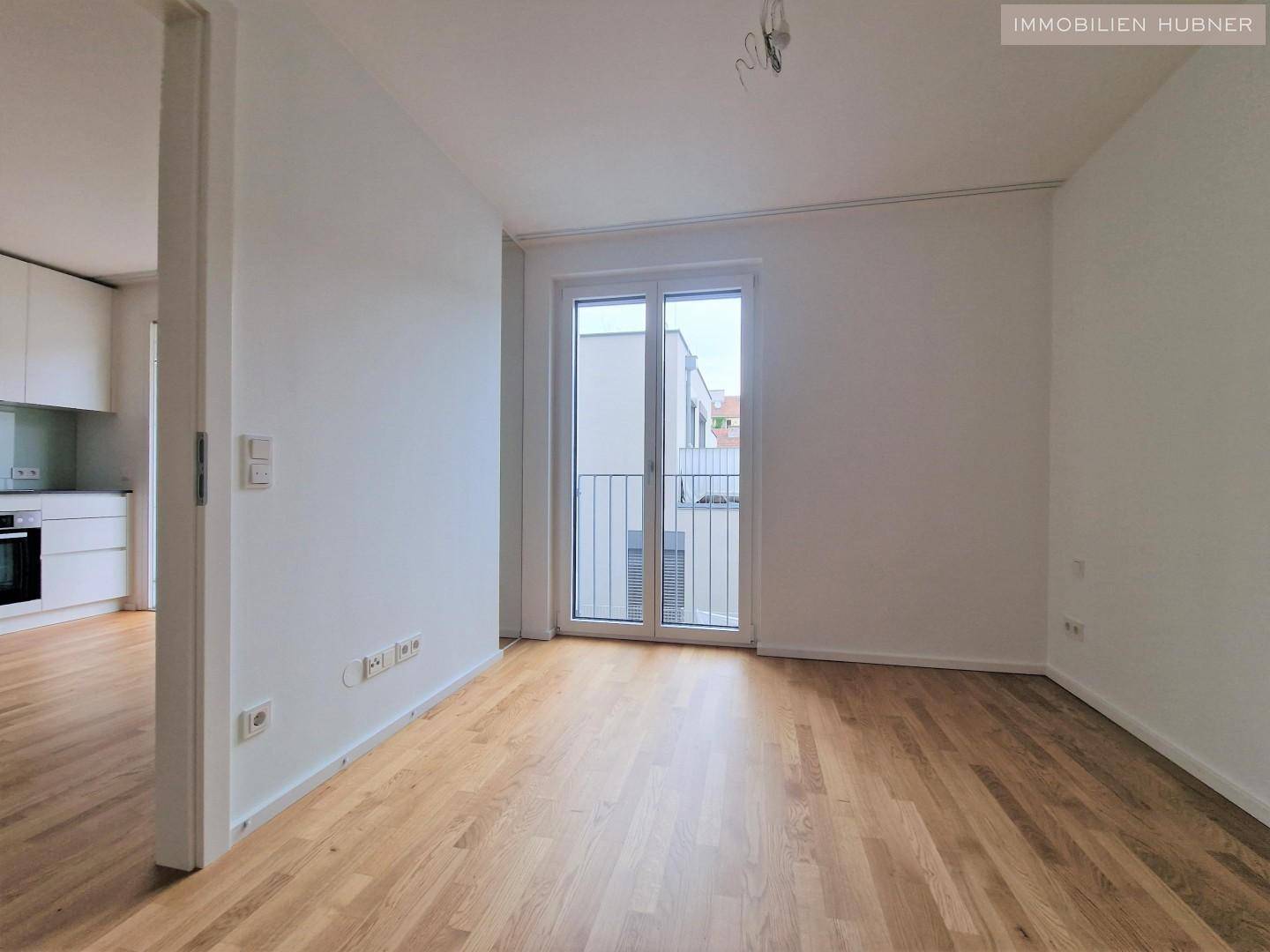 Lichtdurchfluteter Wohnbereich mit Parkettboden und Zugang zu einem französischen Balkon, ideal für frische Luft.
