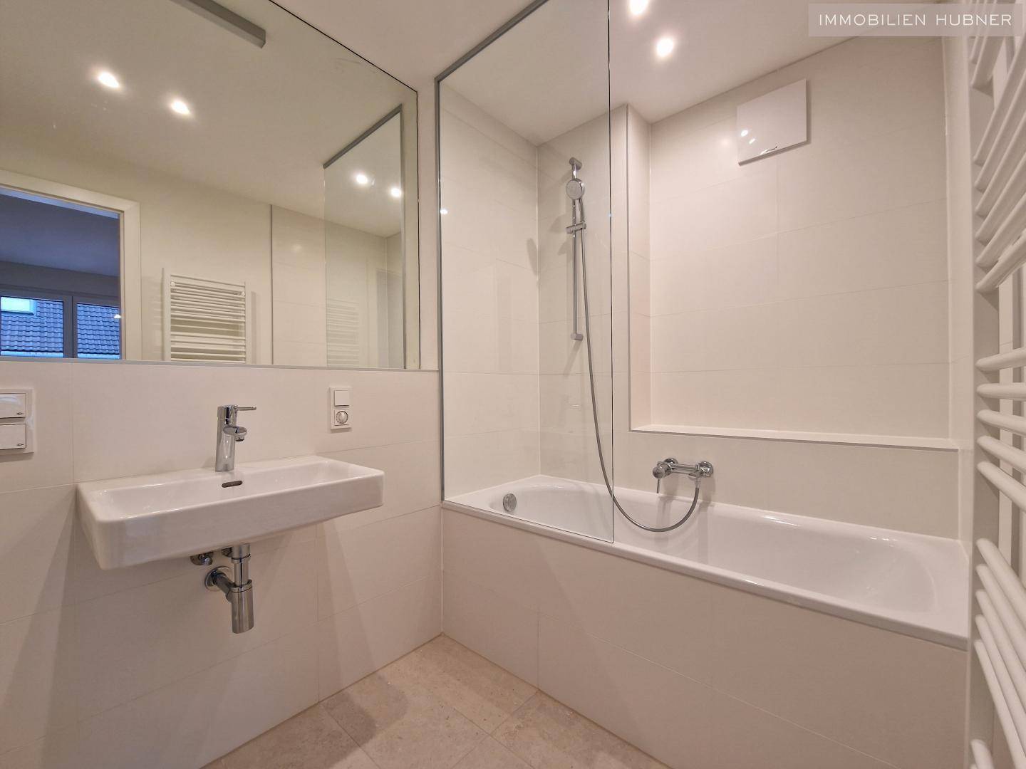 Modernes Badezimmer mit Badewanne, integrierter Dusche, Einzelwaschbecken und großem Spiegel.