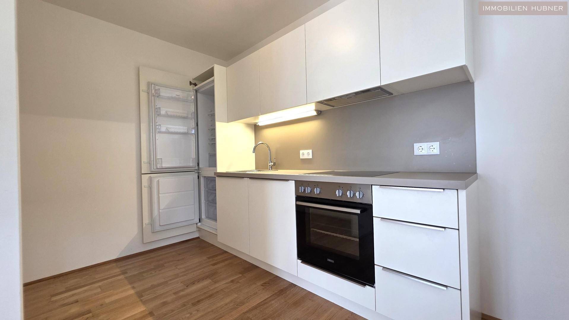 Moderne Küchenzeile mit weißen Schränken, integriertem Backofen und Kühlschrank, praktisch und funktional.