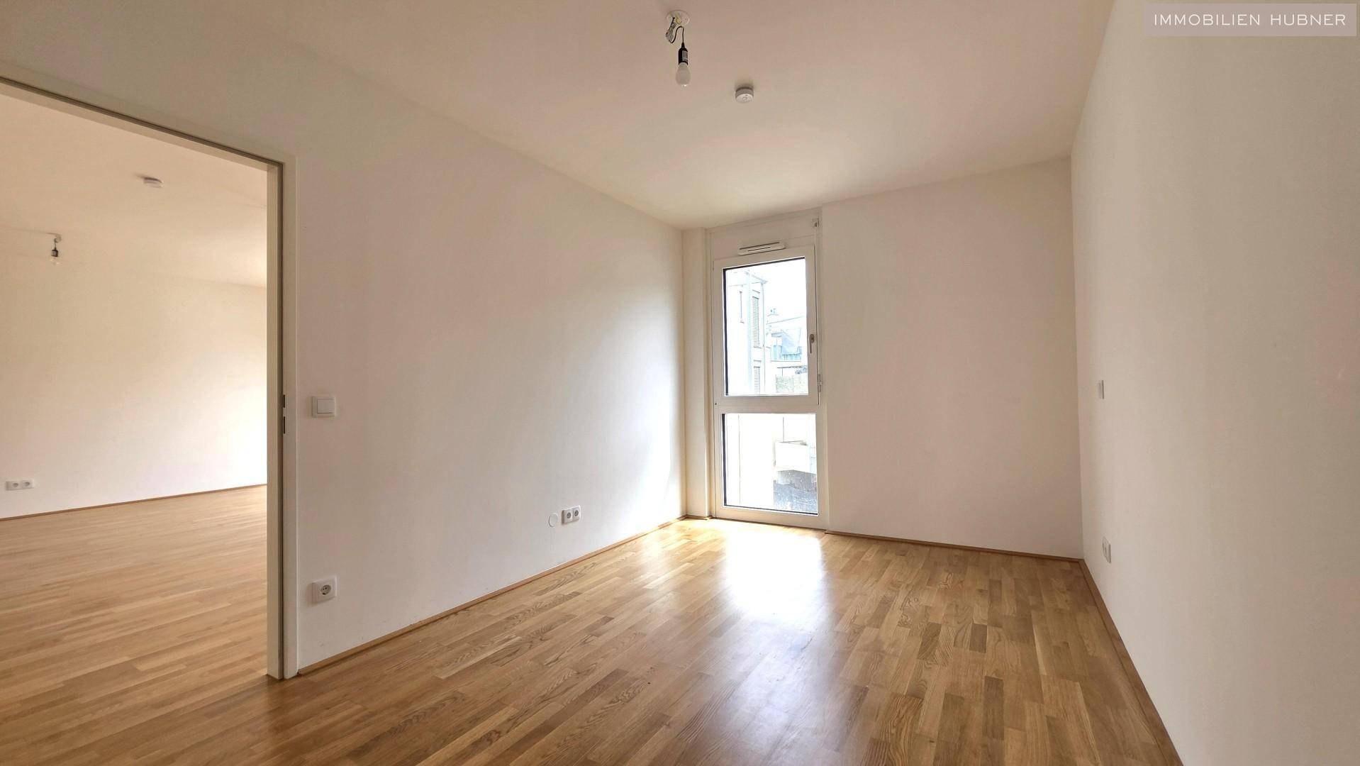 Helles Schlafzimmer mit Parkettboden und Zugang zu einem kleinen Balkon oder französischen Balkon.