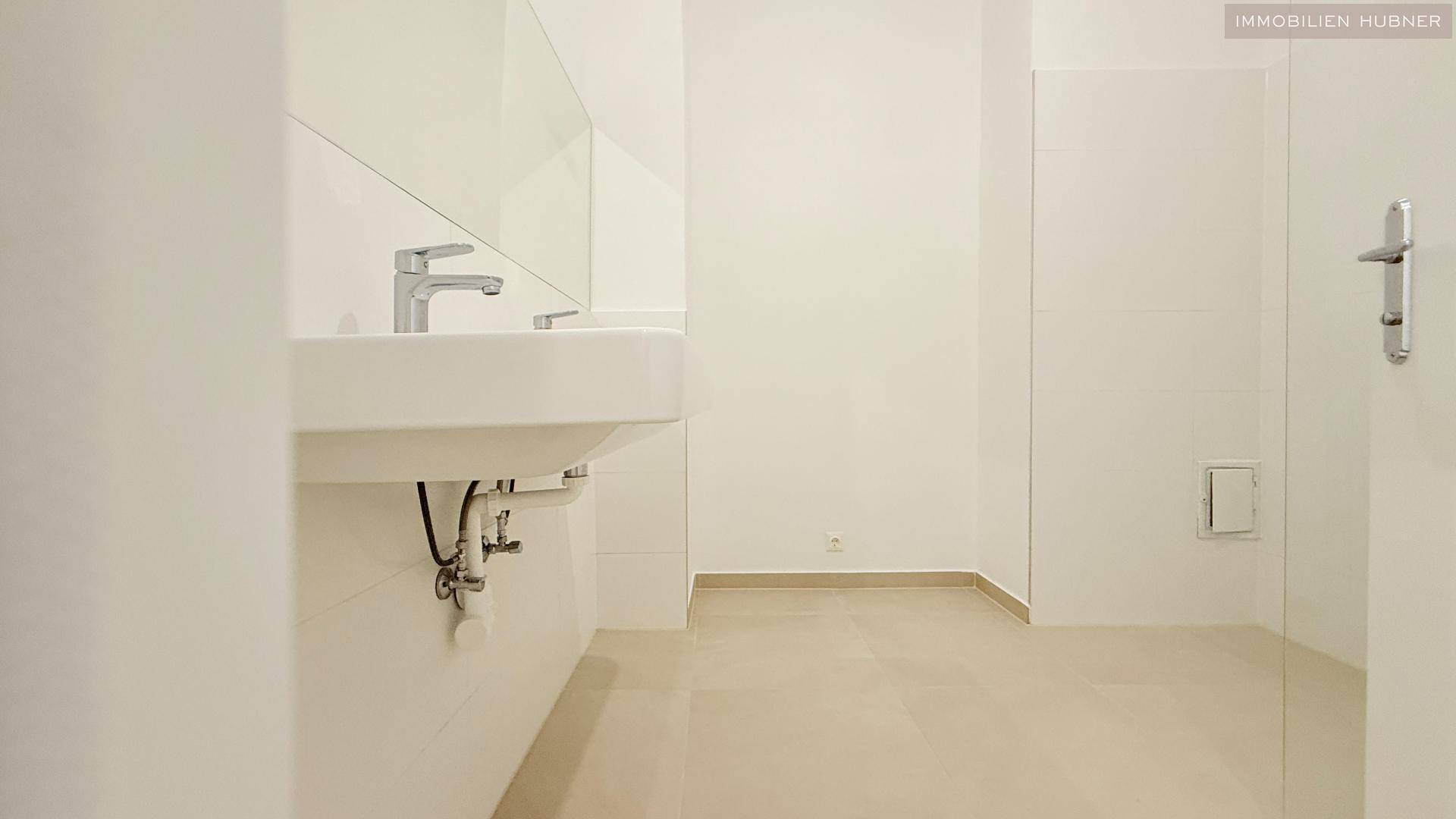 Modernes Badezimmer mit elegantem Einzelwaschbecken und großem Spiegel, in hellen Farbtönen gehalten.