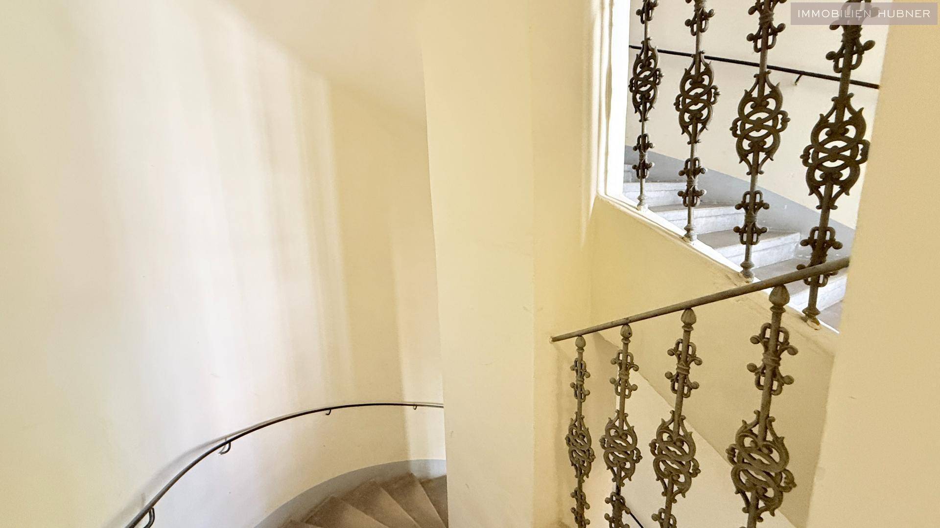 Elegantes Treppenhaus mit kunstvollem Metallgeländer, führt zu den oberen Etagen des Gebäudes.
