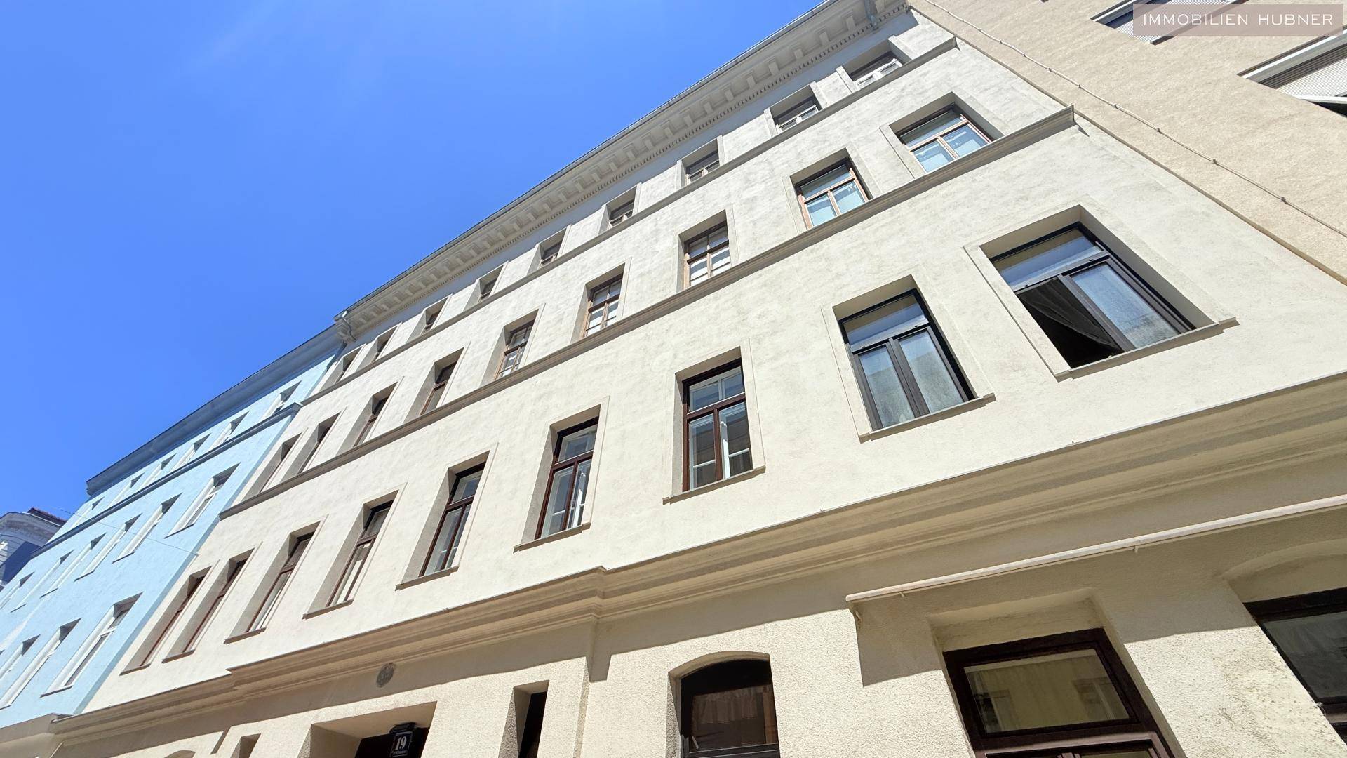 Klassische Gebäudefassade mit vielen Fenstern und traditioneller Architektur, unter blauem Himmel.