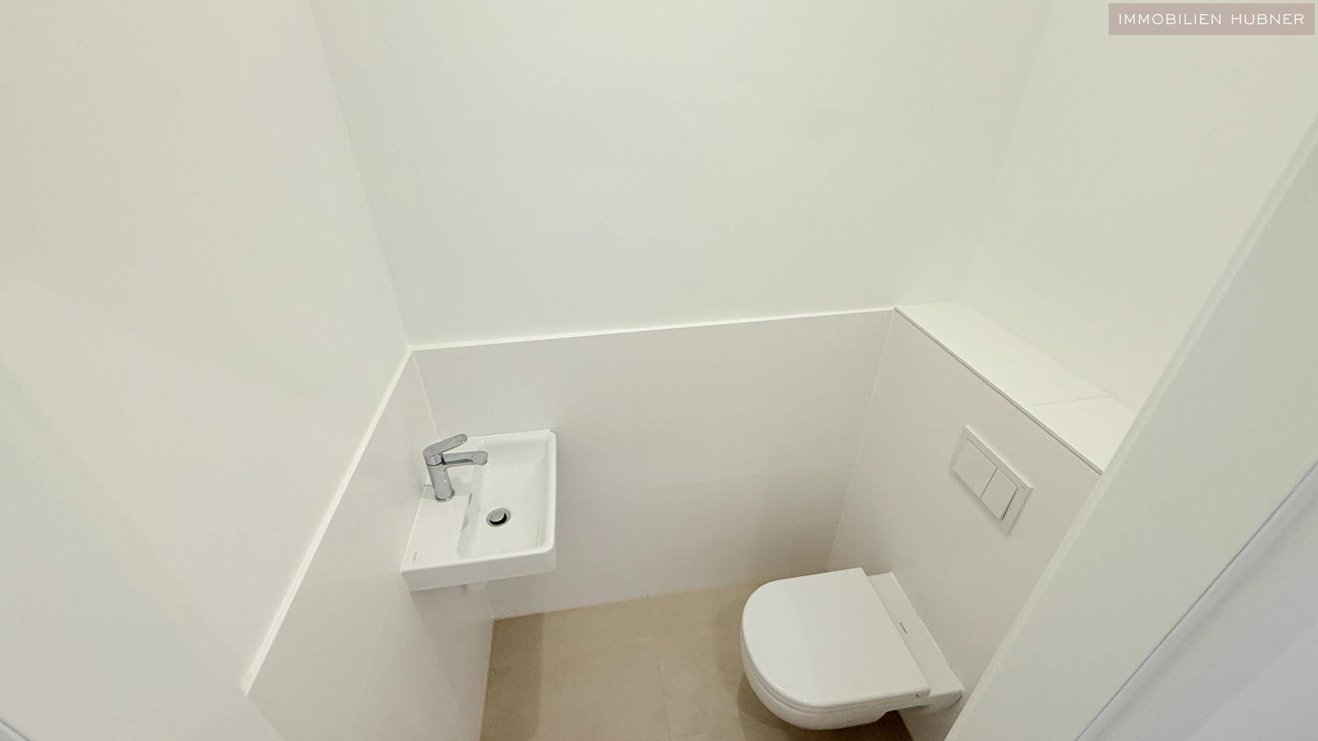 Kompaktes Gäste-WC mit wandhängender Toilette und kleinem Waschbecken, funktional und modern.