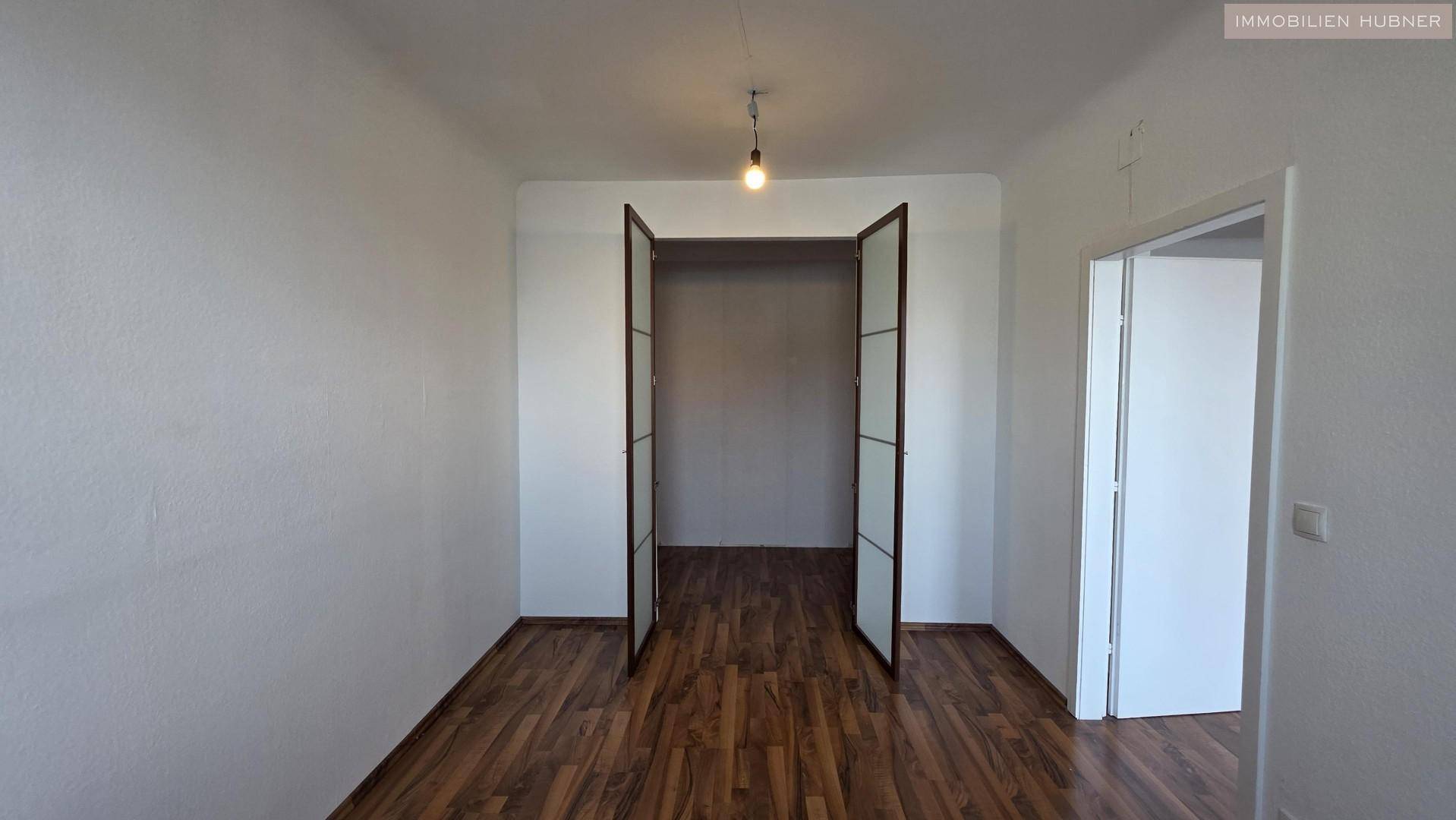 Heller Raum mit Holzboden und offenem Durchgang, vielseitig nutzbar als Schlaf- oder Arbeitszimmer.