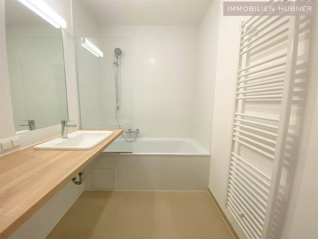 Modernes Badezimmer mit Badewanne, Dusche, Einzelwaschbecken und beheiztem Handtuchhalter.