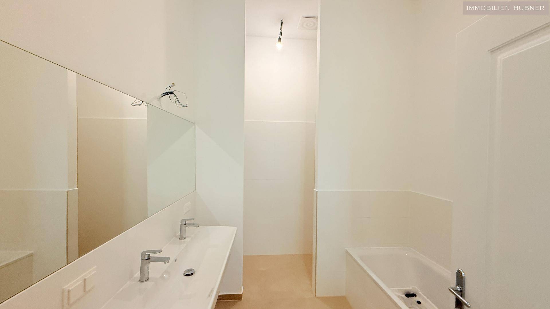 Modernes Badezimmer mit Doppelwaschbecken, großer Spiegelfläche und integrierter Badewanne.